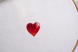 corazón rojo a punto de ser terminado de rellenar, bordado sobre tela Aida o cuadrillé blanco en su bastidor redondo de madera