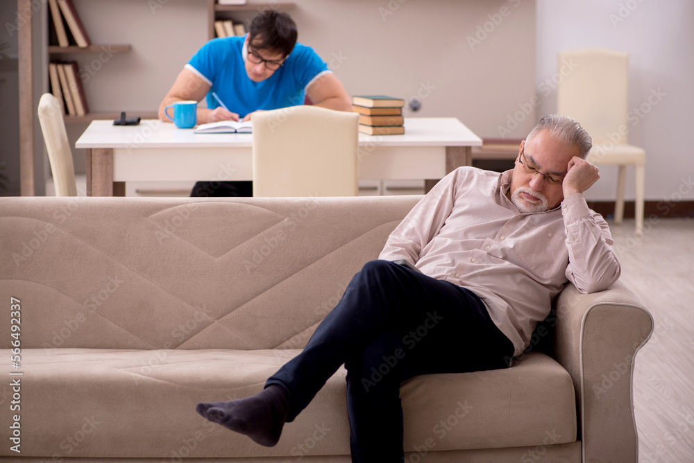 Young male student and his grandfather at home Young male student and his grandfather at home
