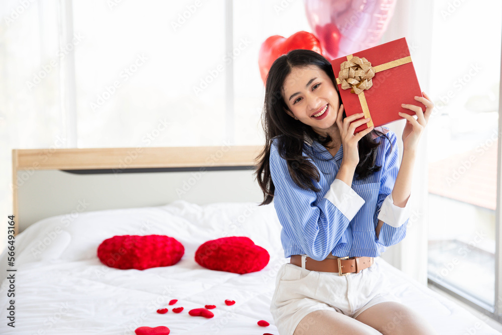 Smiling happy woman in love with gift box and rose in bedroom,Valentine's Day concept. Smiling happy woman in love with gift box and rose in bedroom,Valentine's Day concept.