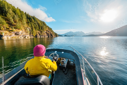 Woman Driving Motor Boat in Amazing Nature Landscape at Sunset in Coastal British Columbia Near Bute, Toba Inlet and Campbell River. Whale Watching Tourist Travel Destination, Canada