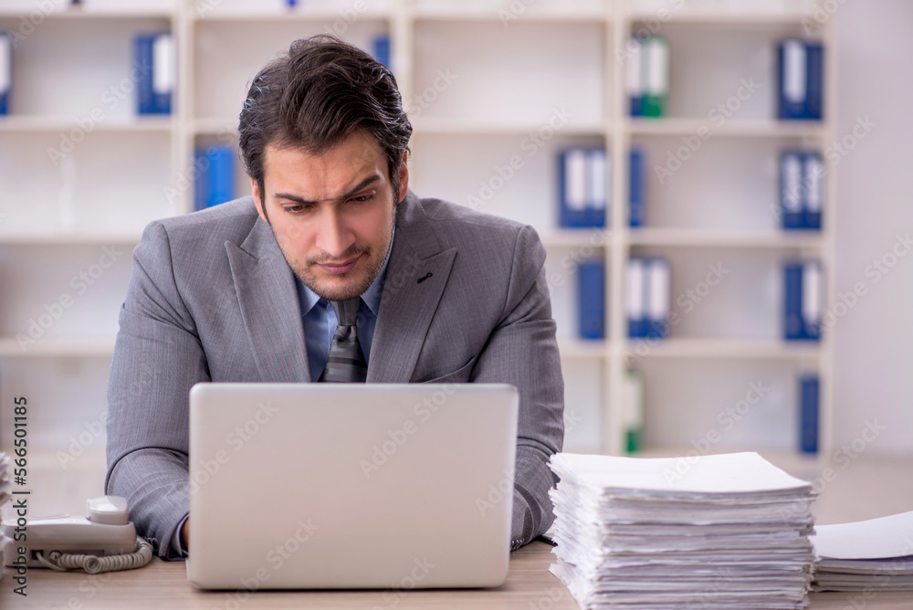 Young male employee and too much work at workplace Young male employee and too much work at workplace