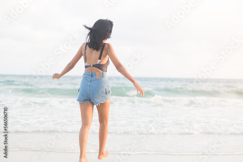 Portrait Happy Girl Running on Sand Beach with Blue Sea,Slim Fit Women with Short Jeans Stand at Ocean Coast,Authentic Female Skin Tan and Black Hair Asian,Tourism Travel Tropical Summer Holiday.
