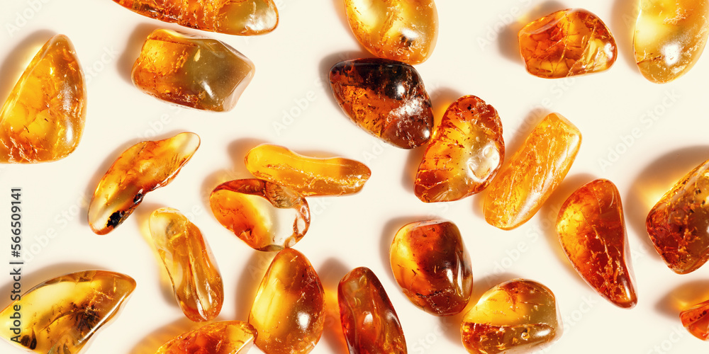 Natural gemstones of amber as background, transparent stones yellow orange colors. Natural rocks beige monochrome. Top view Amber textured gems. Aesthetic wallpaper, banner with uncut stones. Natural gemstones of amber as background, transparent stones yellow orange colors. Natural rocks beige monochrome. Top view Amber textured gems. Aesthetic wallpaper, banner with uncut stones.