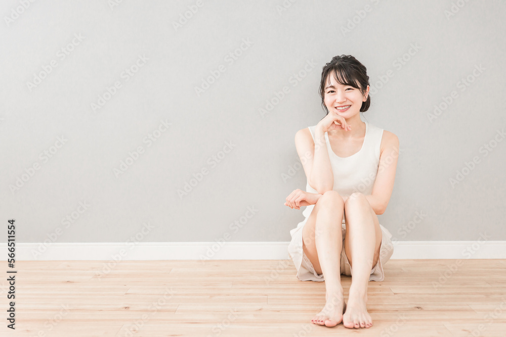 Fototapeta premium 家のリビングに座る美人のアジア人女性（美容・ダイエット・エステ・脱毛・美脚・スキンケア・カメラ目線） 