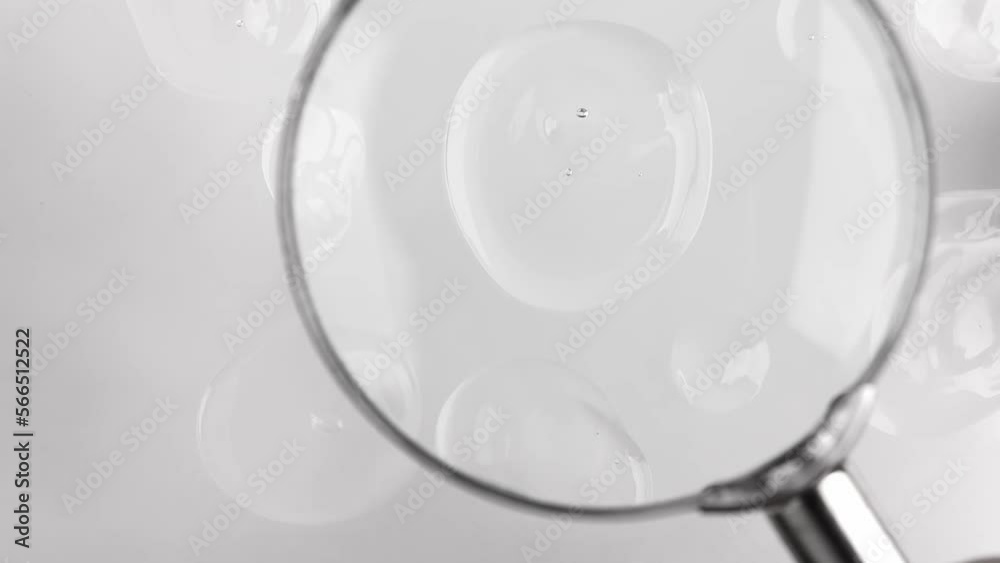 Cosmetic texture closeup top view. Drops of transparent liquid hyaluronic acid with bubbles on a gray background.