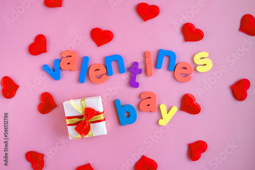 Valentine's Day greeting card with colorful letters and red hearts on a pink background