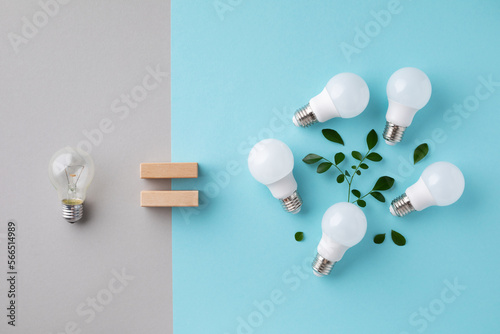 Modern led lights with green leaves energy saving eco concept against incandescent lightbulbs top view. Power efficiency and nature protection idea.