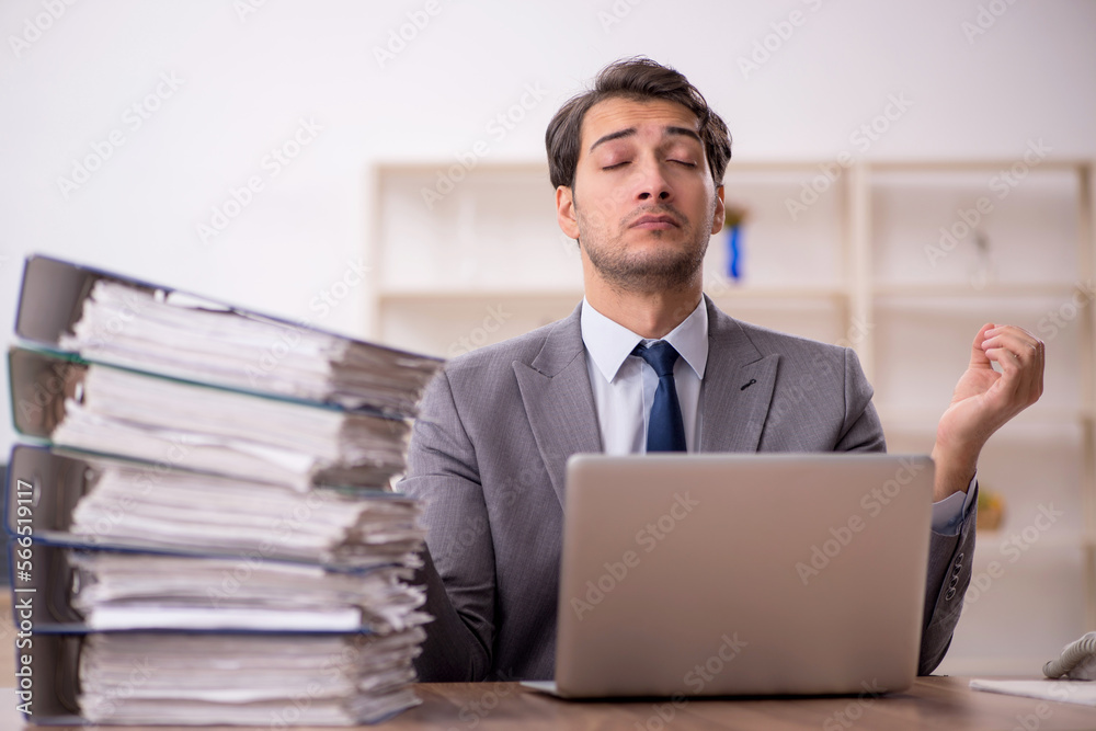 Young male employee and too much work in the office Young male employee and too much work in the office