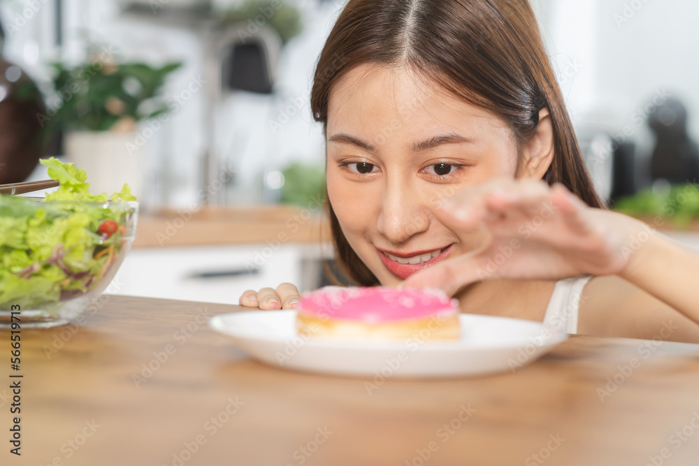 Diet, Dieting happy asian young woman, girl choose, choice eating pink sweet doughnut instead of choosing green salad, eat food good healthy, health when hungry at home. Weight loss person concept. Diet, Dieting happy asian young woman, girl choose, choice eating pink sweet doughnut instead of choosing green salad, eat food good healthy, health when hungry at home. Weight loss person concept.
