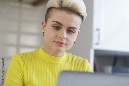 Portrait of female programmer coding on computer at home. Young woman with short hair works freelance with a laptop photo