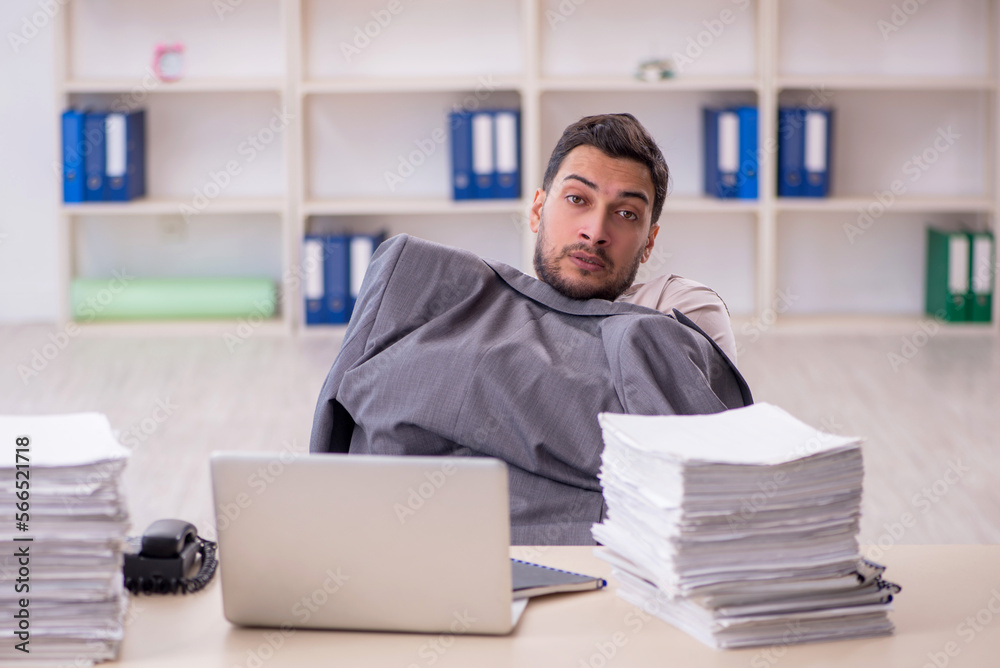 Fototapeta premium Young male employee unhappy with excessive work in the office