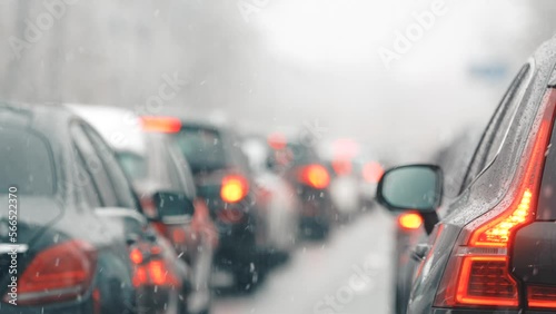 Rush hour traffic. 4k video during a winter morning snowfall, view to car rear lights standing in traffic. Transportation industry.