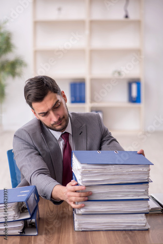 Young male employee and too much work in the office