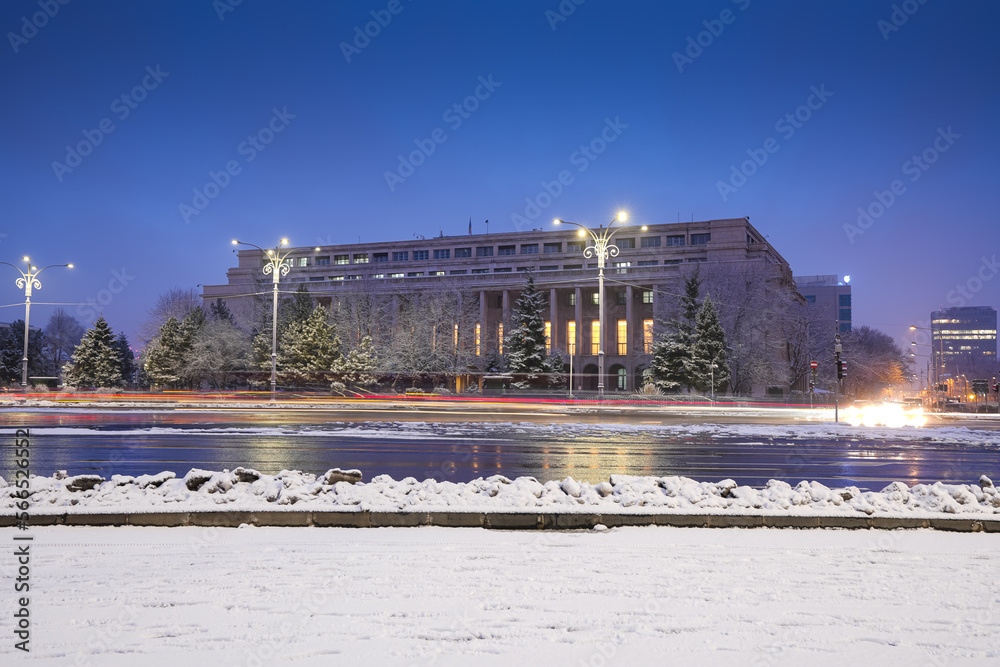 Naklejka premium Long exposure photo during a winter morning in Bucharest, view to Victoria Palace (Romanian Government building) with rush hour traffic in foreground.