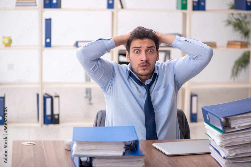 Young male employee and too much work in the office Young male employee and too much work in the office