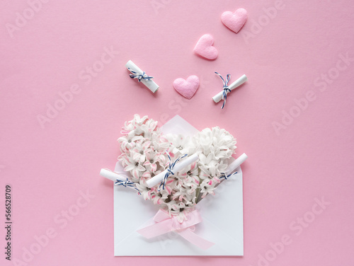 Ein Briefkuvert gefüllt mit weißen Blüten und kleinen Wunschzetteln. Flat lay, rosa Hintergrund. © Sonja Rachbauer