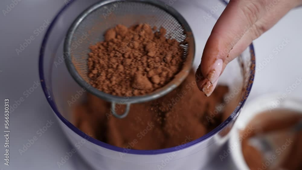 A woman hands sprinkles cocoa powder with a sieve, close up A woman hands sprinkles cocoa powder with a sieve, close up