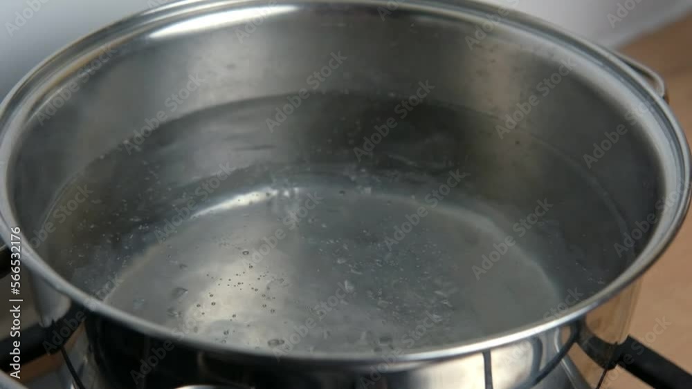 Clean boiling water in a hot pan. Pot of boiling water with many bubbles over modern kitchen background. Slow motion shot. High angle closeup. Transparent water bubbling in a saucepan on burning stove Clean boiling water in a hot pan. Pot of boiling water with many bubbles over modern kitchen background. Slow motion shot. High angle closeup. Transparent water bubbling in a saucepan on burning stove