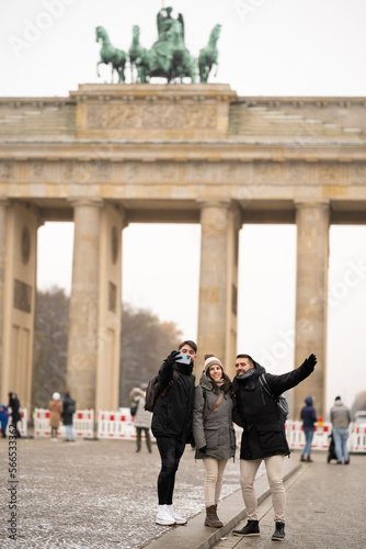 Group of friends taking a selfie with the Brandenburg Gate in the background in Berlin, Germany - tourism concept