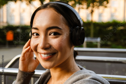 Young asian woman in headphones smiling during workout on playground