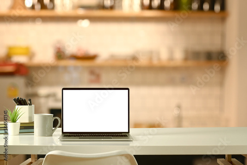 Laptop computer white table in modern with soft and warm light. Copy space and blank screen for your advertise design © Prathankarnpap