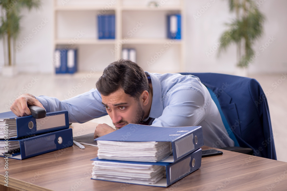 Young male employee and too much work in the office Young male employee and too much work in the office