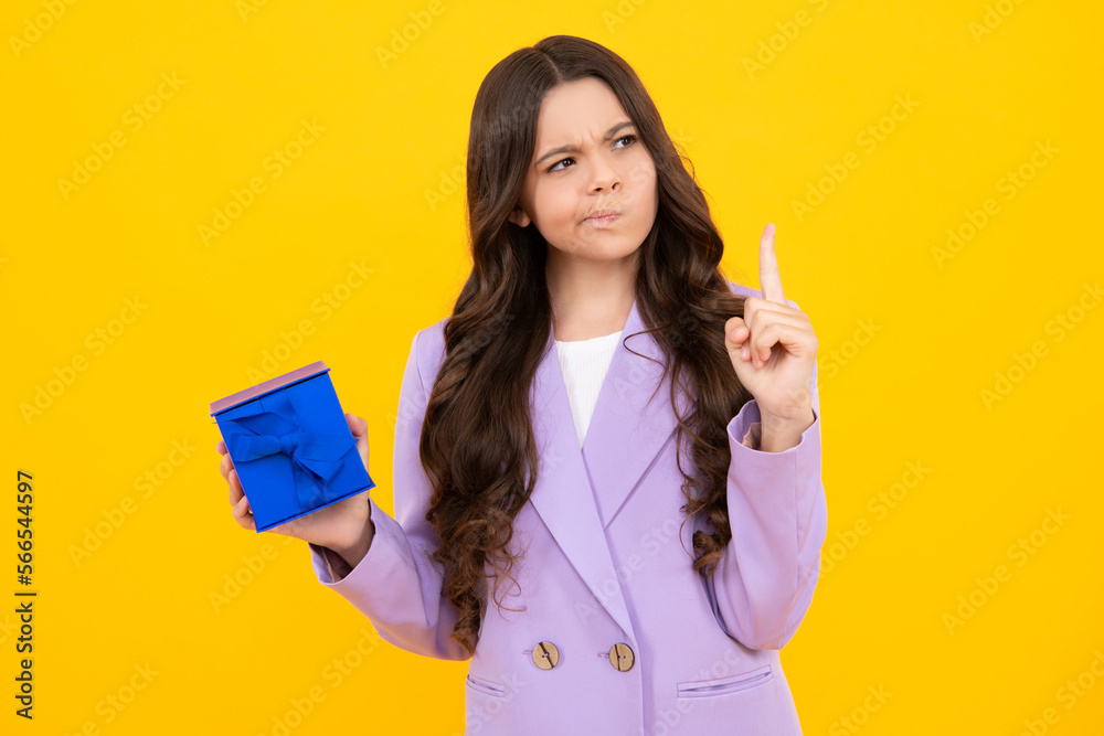 Child with gift present box on isolated studio background. Gifting for kids birthday. Thinking teenager girl, thoughtful emotion. Child with gift present box on isolated studio background. Gifting for kids birthday. Thinking teenager girl, thoughtful emotion.