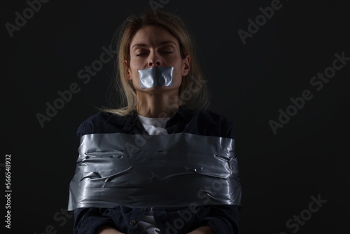 Woman taped up and taken hostage on dark background