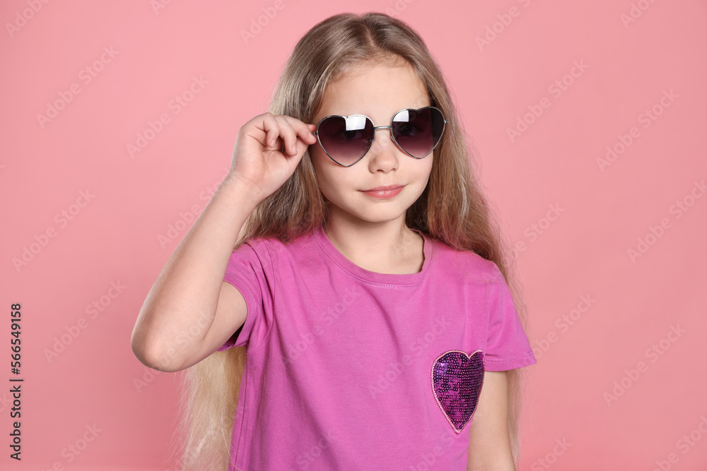 Girl wearing stylish sunglasses in shape of hearts on pink background Girl wearing stylish sunglasses in shape of hearts on pink background