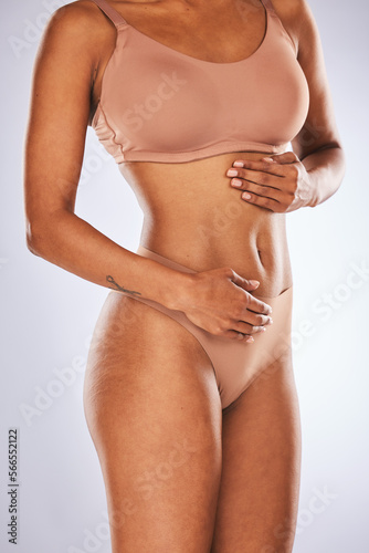 Stomach, wellness and woman in studio for diet, weight loss and detox against a grey background. Hands, belly and girl model feeling results of liposuction, tummy tuck or cosmetic treatment isolated