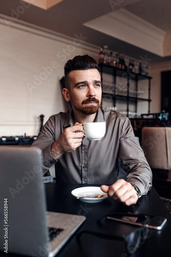 Businessman is working with his laptop and drinking coffee in cafe