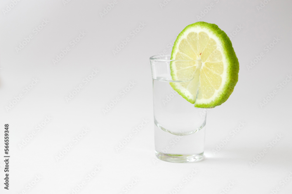 Shot of tequila with a slice of lime on white Shot of tequila with a slice of lime on white