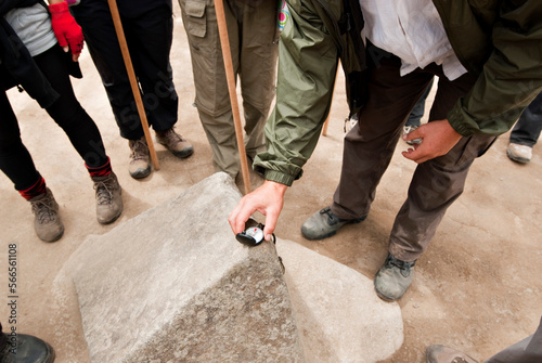 A young man places a compass on a rock that the Incan's perfectly carved in the four cardinal directions to use for navigation.