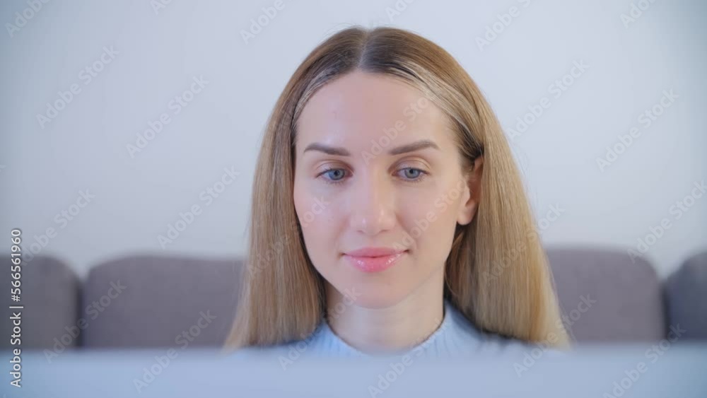 Young adult blonde woman working on a computer at home. Natural looking white female person in 30s using a laptop for work in the living room Young adult blonde woman working on a computer at home. Natural looking white female person in 30s using a laptop for work in the living room