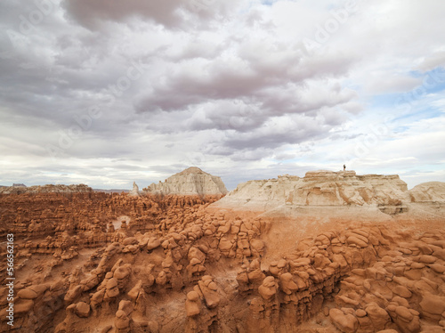 Hikers stand on the summit of a high mesa overlooking the vast field of hoodoos at Goblin Valley State Park, Utah.