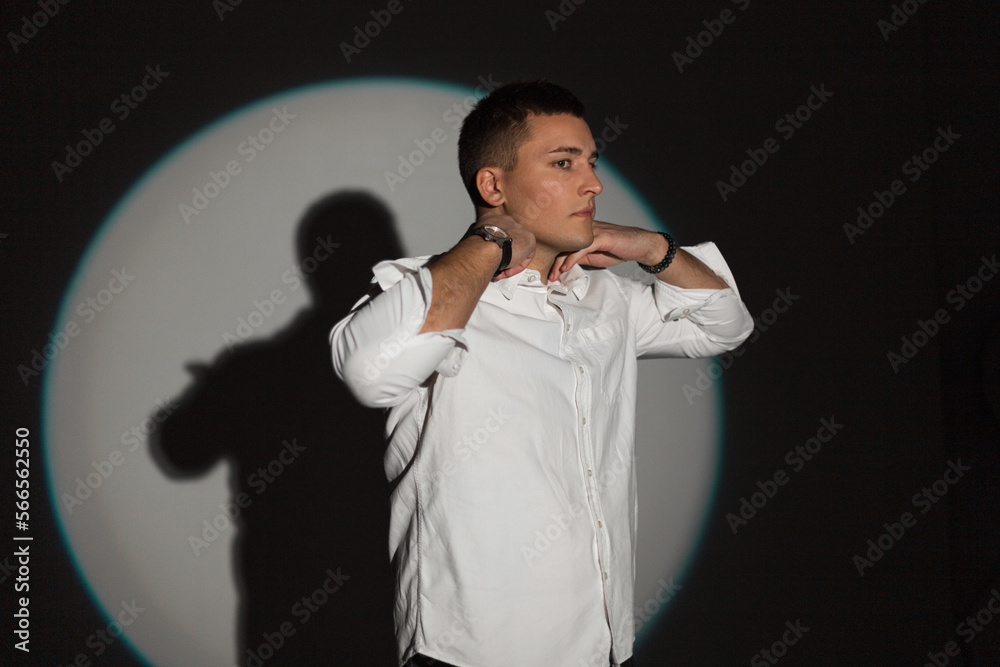 Handsome business professional man in fashion white shirt on a black background with circle light at party Handsome business professional man in fashion white shirt on a black background with circle light at party