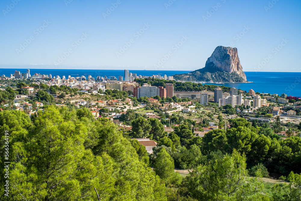 Naklejka premium view from Olta mountain on small houses, trees and apartment buildings and Ifach rock and Mediterranean sea