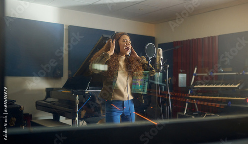 Headphones, singing or woman with studio microphone in album recording, evening audio or radio music at night. Singer, musician or artist in production song, voice media or sound performance practice