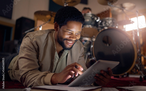 Black man musician, tablet and technology in music studio for social media, lyrics research or internet browsing. Tech, digital touchscreen and male artist web scrolling or editing audio at night.