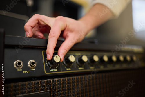 Hands, amplifier volume and music studio with female musician or producer with equipment. Technology, audio and hand of woman adjusting sound nob on dj machine or radio amp in creative workplace. photo