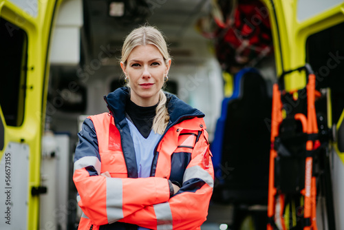 Tableau sur toile Portrait of young woman doctor standing in front of ambulance car