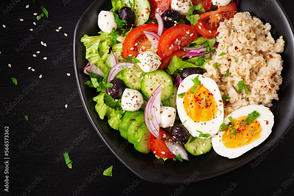 Healthy breakfast. Greek inspired savory oatmeal with fresh cucumber, tomatoes, olives, lettuce, mozzarella cheese and boiled egg. Top view Healthy breakfast. Greek inspired savory oatmeal with fresh cucumber, tomatoes, olives, lettuce, mozzarella cheese and boiled egg. Top view