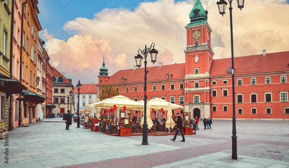 Warsaw, Poland. Royal castle on Zamkowy Square. Street cafe with tables. High tower clock ove clear evening sky