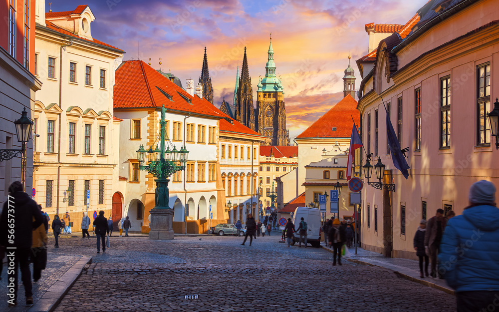 Prague, Czech Republic. Picturesque street of old town. View to Saint Vitus Cathedral tower with spires. Evening sunset