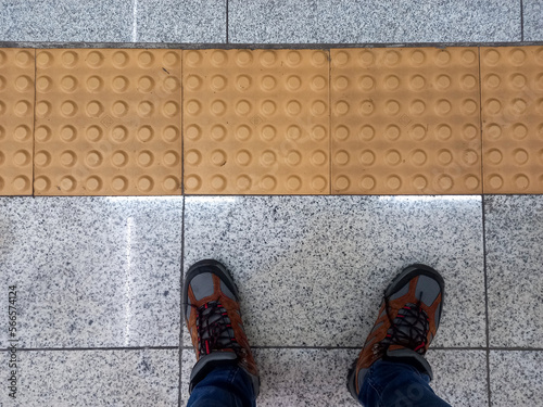 point of view shot of a man look down to his feet on the floor near braille block photo
