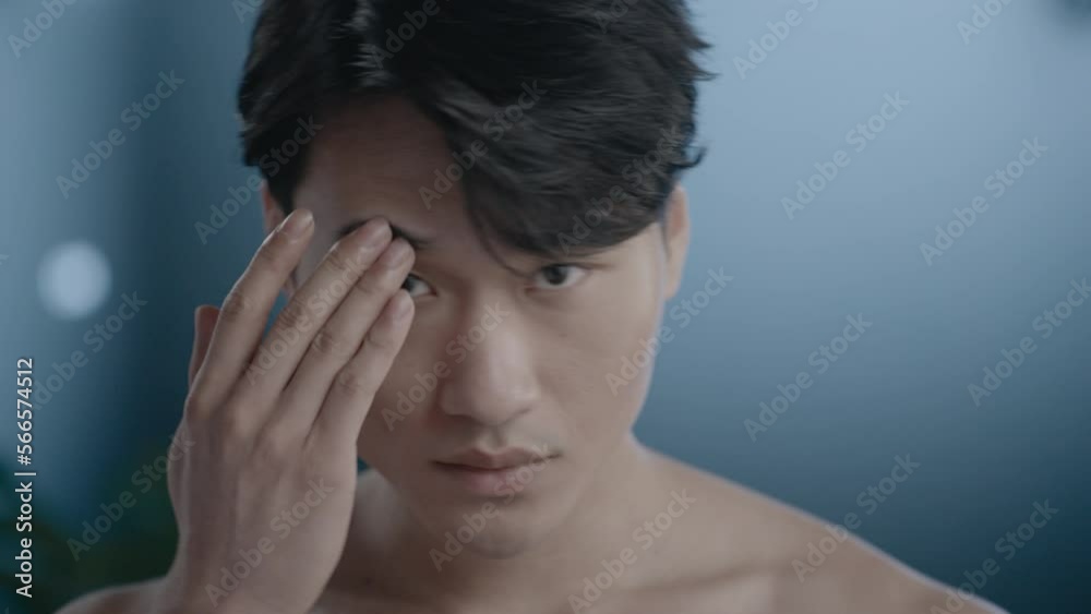 Portrait of young handsome Asian male using cosmetic ceramic face roller in the bathroom, daily skincare routine for healthy skin Portrait of young handsome Asian male using cosmetic ceramic face roller in the bathroom, daily skincare routine for healthy skin