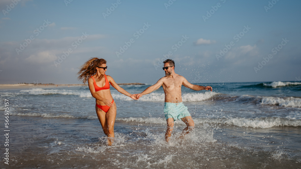 Happy couple enjoying time in sea, running, having fun.
