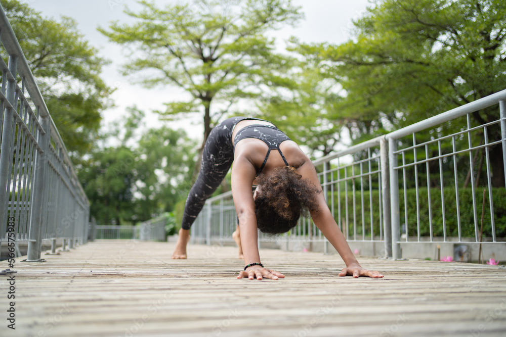 Fototapeta premium Portrait of Black African American woman in yoga class club doing exercise, runing or jogging at public garden park. Outdoor sport and recreation. People lifestyle activity with nature trees view.