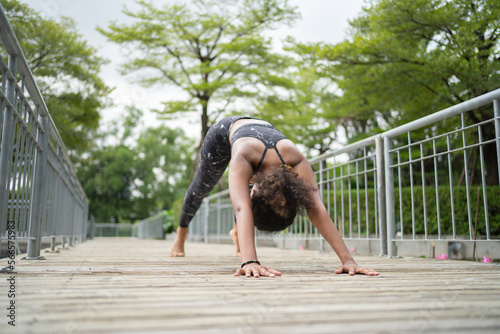 Portrait of Black African American woman in yoga class club doing exercise, runing or jogging at public garden park. Outdoor sport and recreation. People lifestyle activity with nature trees view.