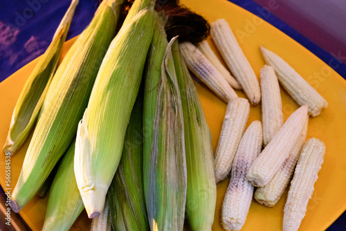 Group of baby corns with and without husk on a plate. closeup shot.
